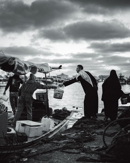 Free Fishermen unloading their day's catch at a dock at dusk, reflecting a daily life scene. Stock Photo