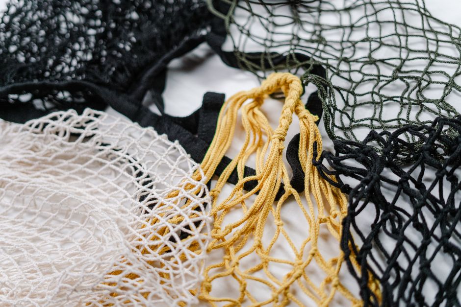 Close-up of reusable mesh bags in black, white, and yellow showcasing eco-friendly shopping options.