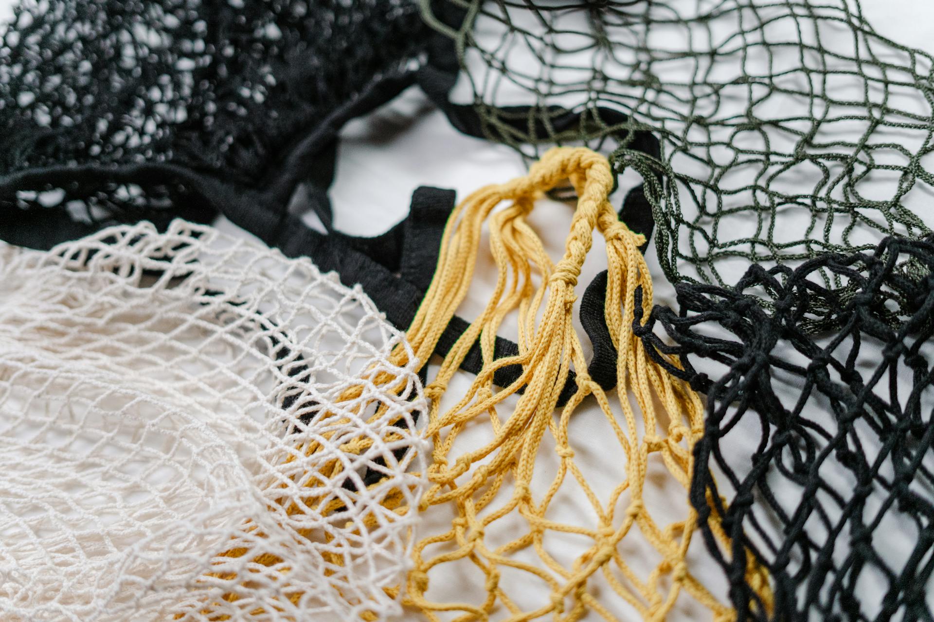 Close-up of reusable mesh bags in black, white, and yellow showcasing eco-friendly shopping options.
