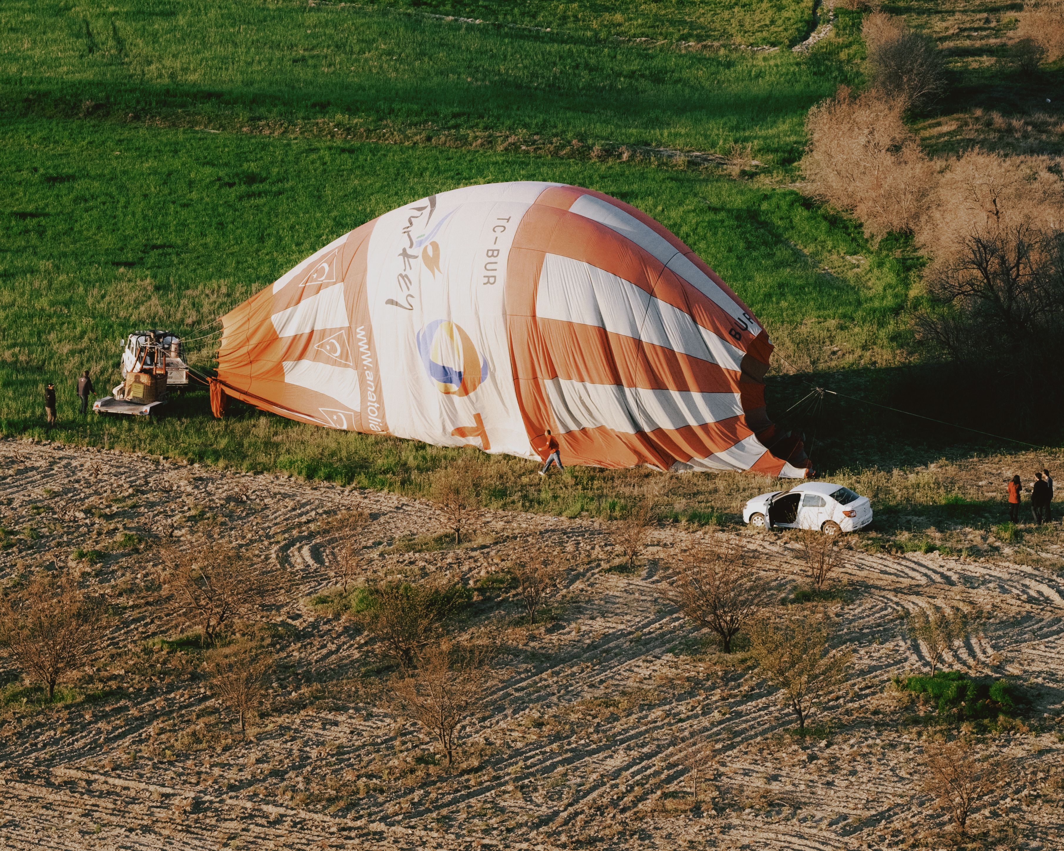 Spectacular Heli for Influencers: Photoshoot in Istanbul with Helicopter Review 2026 - A deflated hot air balloon lying on a vibrant green field with a car nearby, suggesting a post-flight scene.