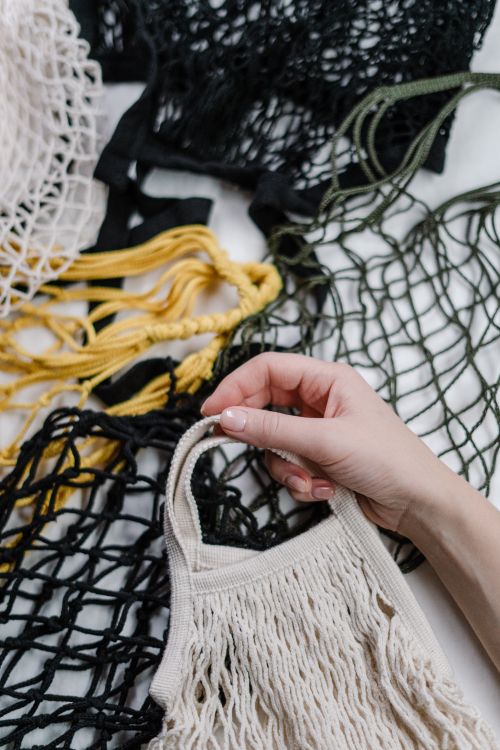 Free Close-up of a hand holding eco-friendly mesh bags in various colors emphasizing zero waste. Stock Photo