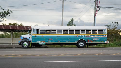 Free Colorful blue school bus parked by the roadside with cloudy sky backdrop. Stock Photo