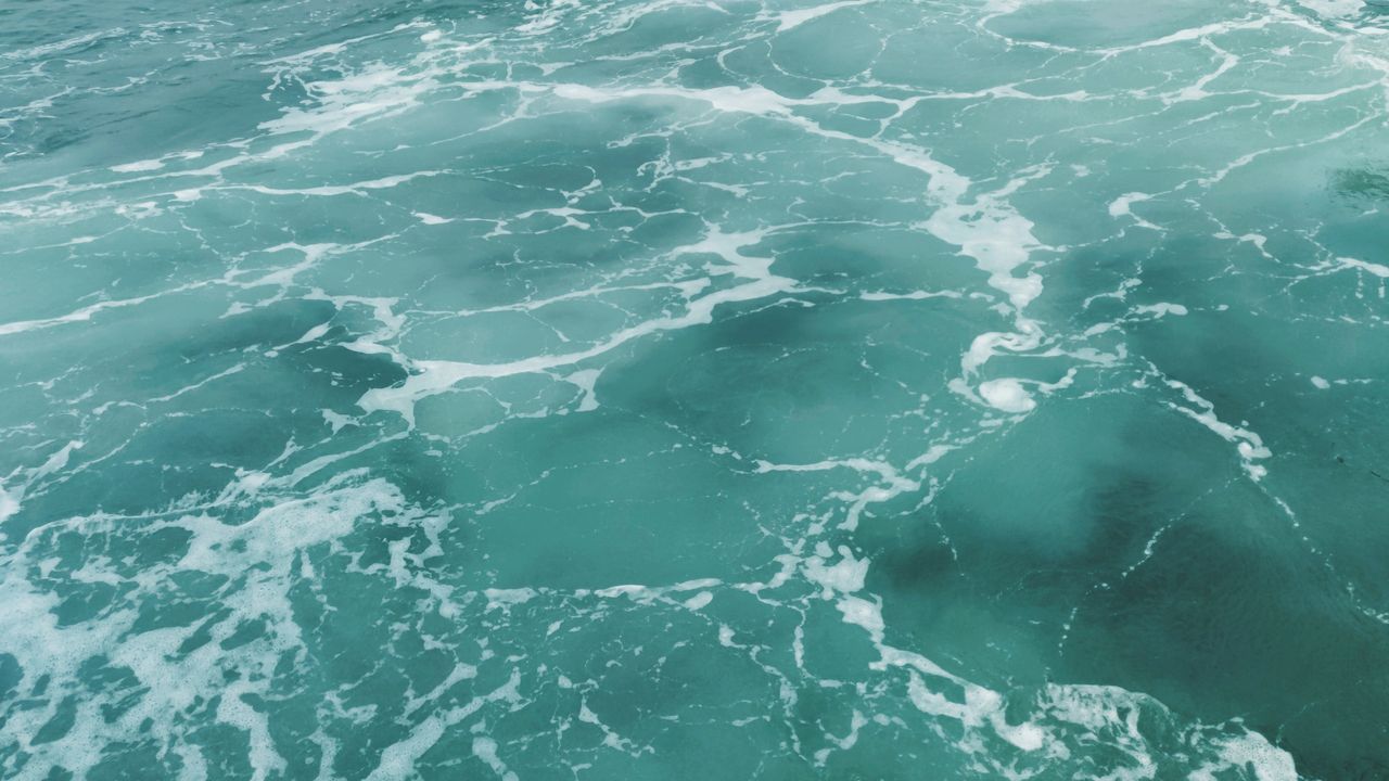 a captivating aerial shot of turquoise ocean waves creating intricate