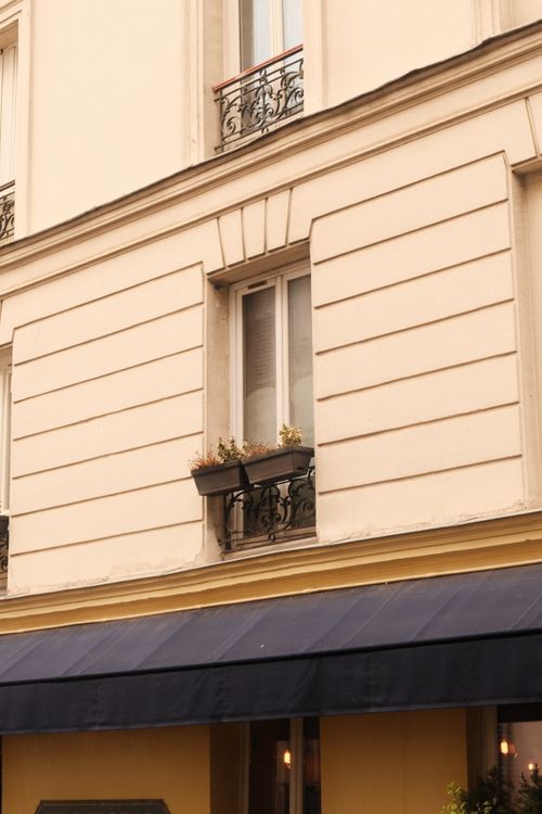 Free Elegant Parisian apartment facade with classic wrought iron balcony and soft lighting. Stock Photo