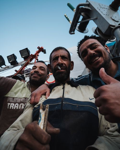 Free Three construction workers smiling and giving a thumbs up, showcasing camaraderie on a work site. Stock Photo