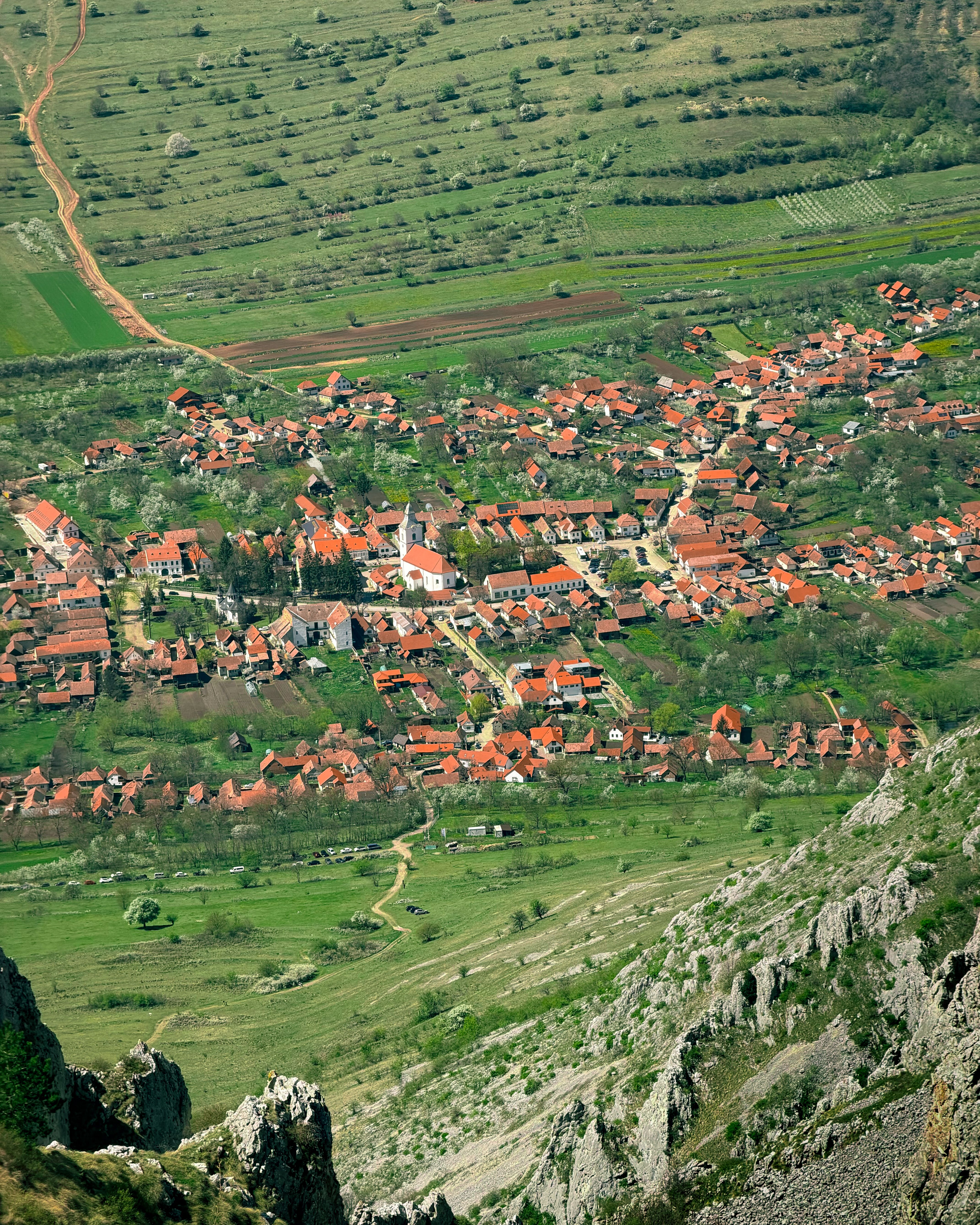 Scenic aerial view of Rimetea village with red rooftops and green landscapes in spring, Romania.