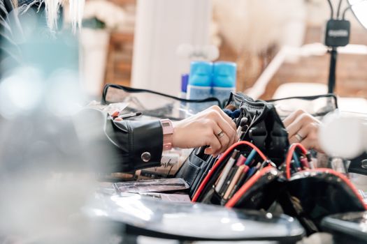 Close-up of a makeup artist organizing a professional cosmetic kit with brushes and tools.