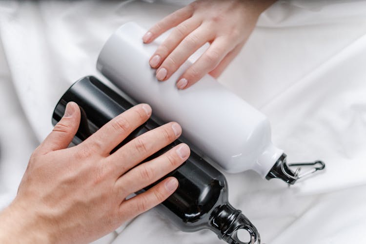 Hands Holding Black And White Tumblers