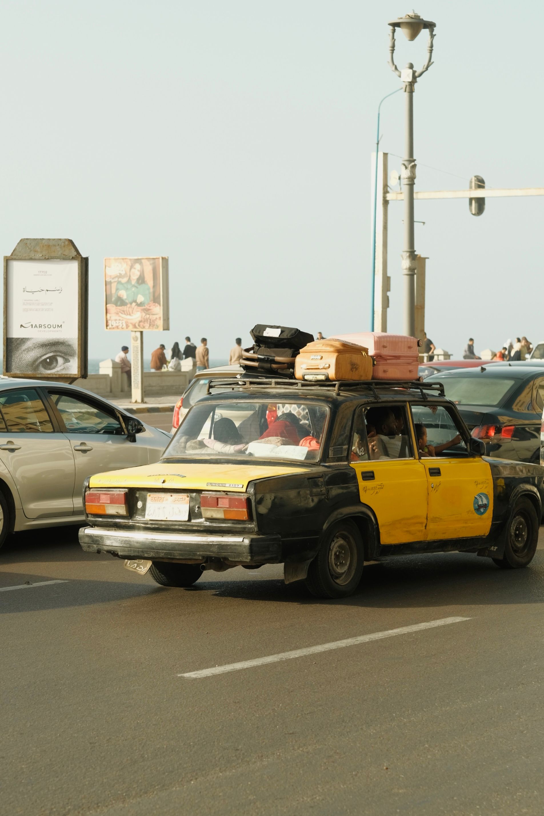 A bustling street scene featuring a classic yellow taxi on the Alexandria Corniche.