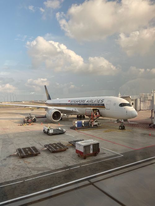 Free Singapore Airlines aircraft parked at Changi Airport with loading equipment nearby. Stock Photo