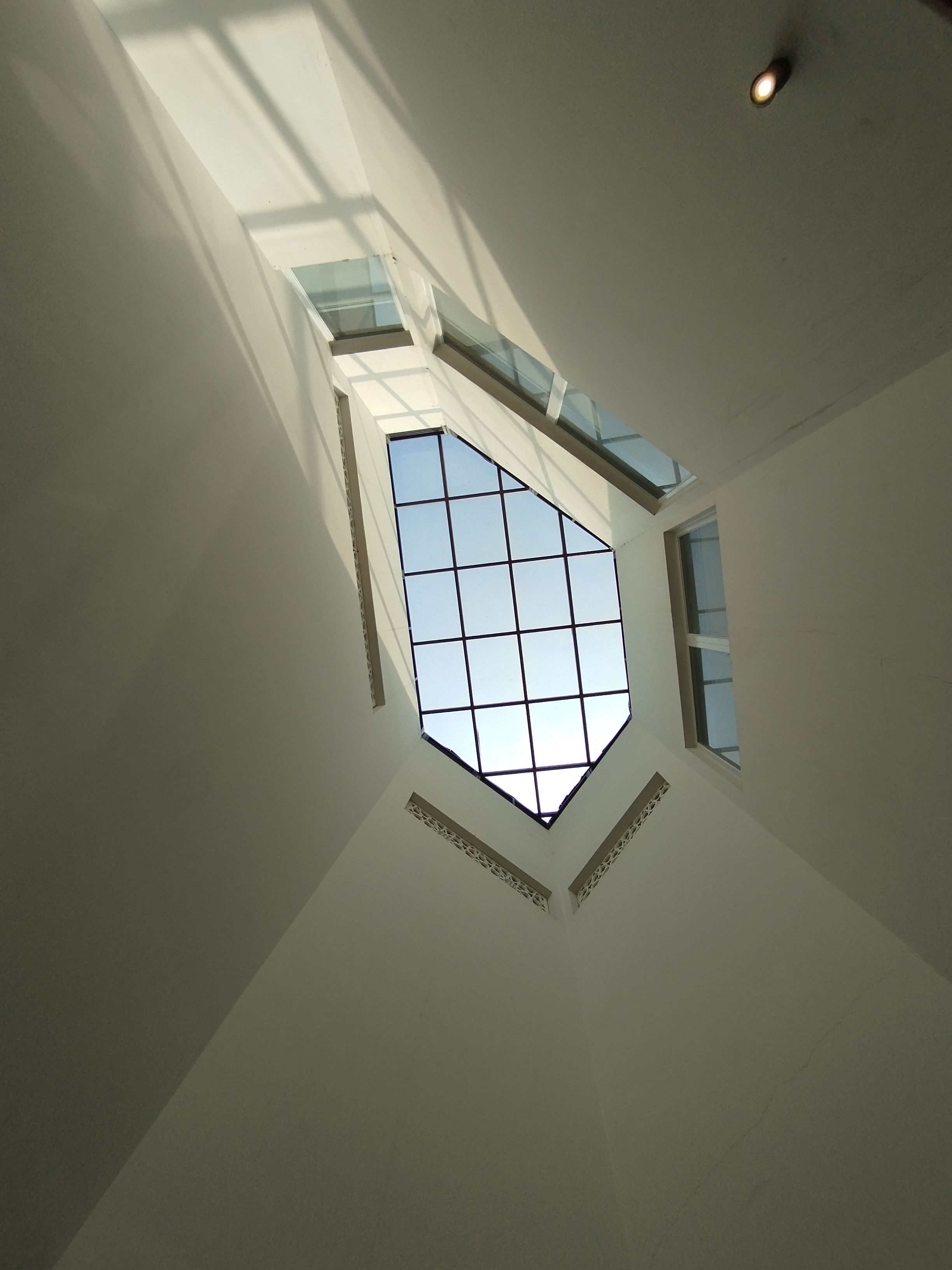 A contemporary interior skylight with a geometric glass pattern casting shadows indoors.