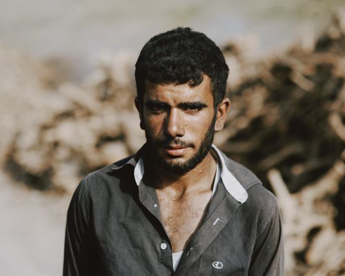 Free Close-up portrait of a young man standing outdoors with a thoughtful expression, soft focus background. Stock Photo