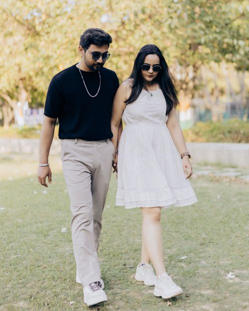 Free A couple holding hands and walking in a sunny garden, embodying romance and connection. Stock Photo