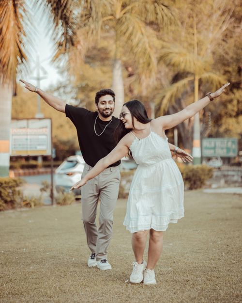 Free A joyful Indian couple enjoying a playful outdoor pre-wedding shoot in a park setting. Stock Photo