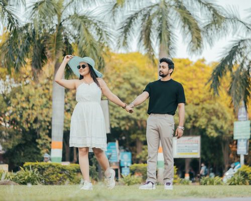 Free A couple holding hands under palm trees on a sunny day, exuding romance. Stock Photo