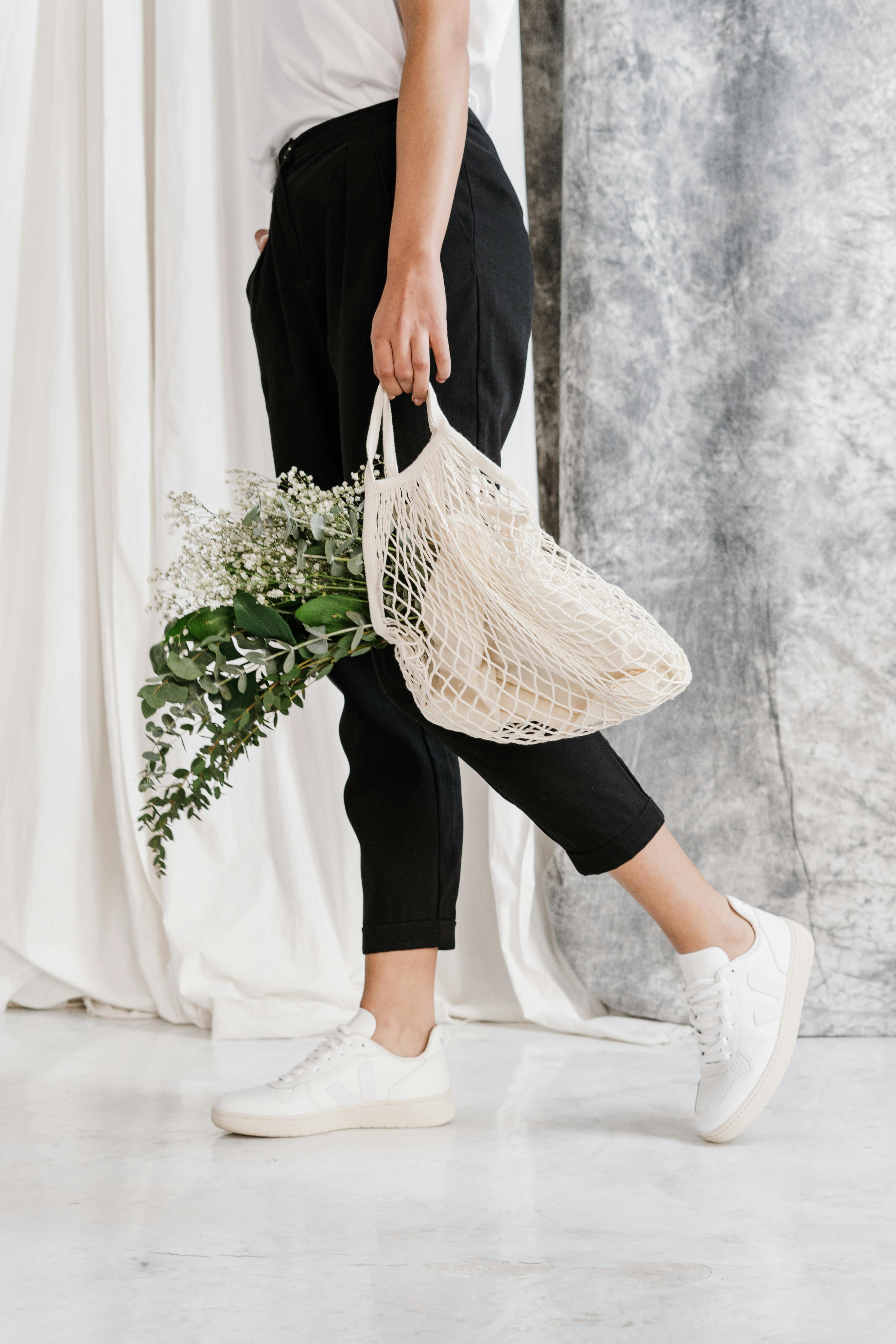 时尚女性手提装满绿植的网袋，倡导环保时尚