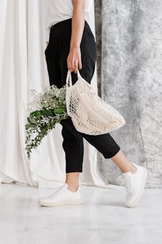 时尚女性手提装满绿植的网袋，倡导环保时尚