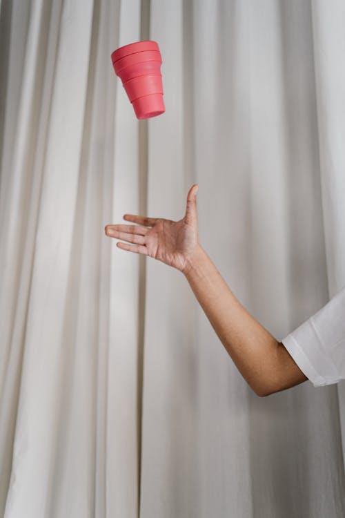 Person Catching Pink Plastic Cup