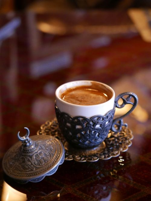 Free A beautifully presented Turkish coffee in an ornate silver cup on a reflective table. Stock Photo