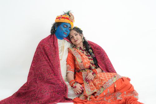 Free A couple dressed as traditional Indian deities with blue face paint in a colorful costume on a white background. Stock Photo