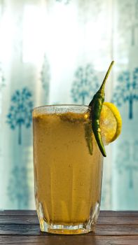 Chilled lemonade with a spicy twist, garnished with green chili and lemon slice, perfect for summer refreshment.