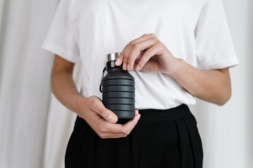 Person In White Shirt Holding Black Rubber Bottle