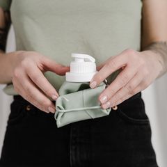Hands rolling up a soft collapsible water bottle with a white cap
