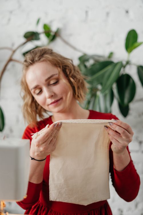 Free Young woman sewing fabric in a cozy indoor setting with natural greenery. Stock Photo