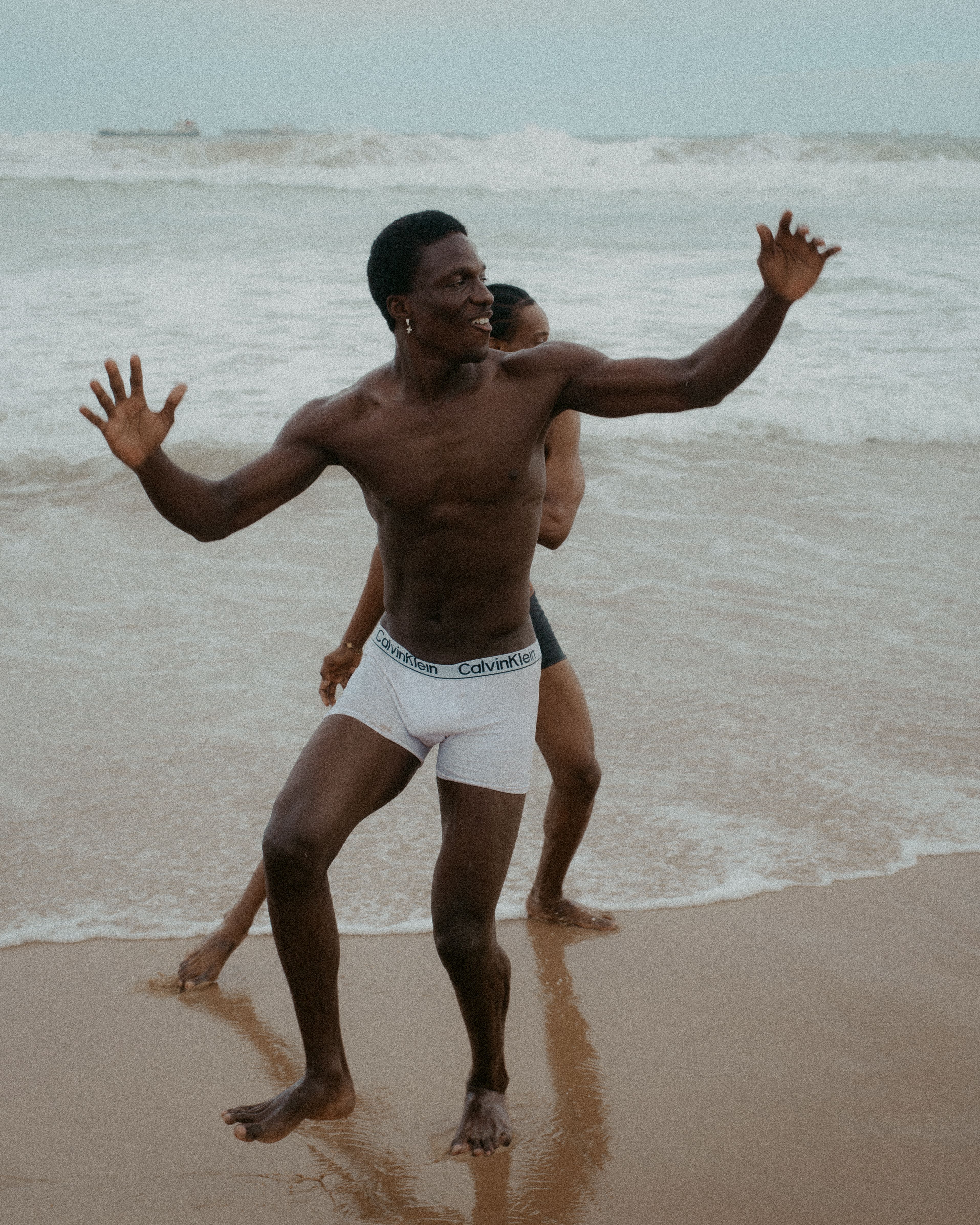 Two adults enjoying a lively dance on Lagos beach, showcasing happiness and freedom.