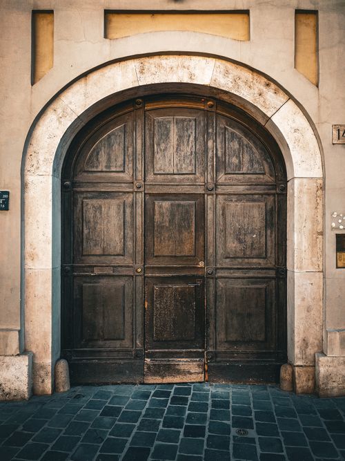 Free A rustic wooden door framed by a stone archway in Budapest, Hungary, showcasing historic architecture. Stock Photo