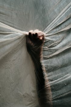 一只手紧紧抓住塑料，用水滴创造出概念图像，发人深省