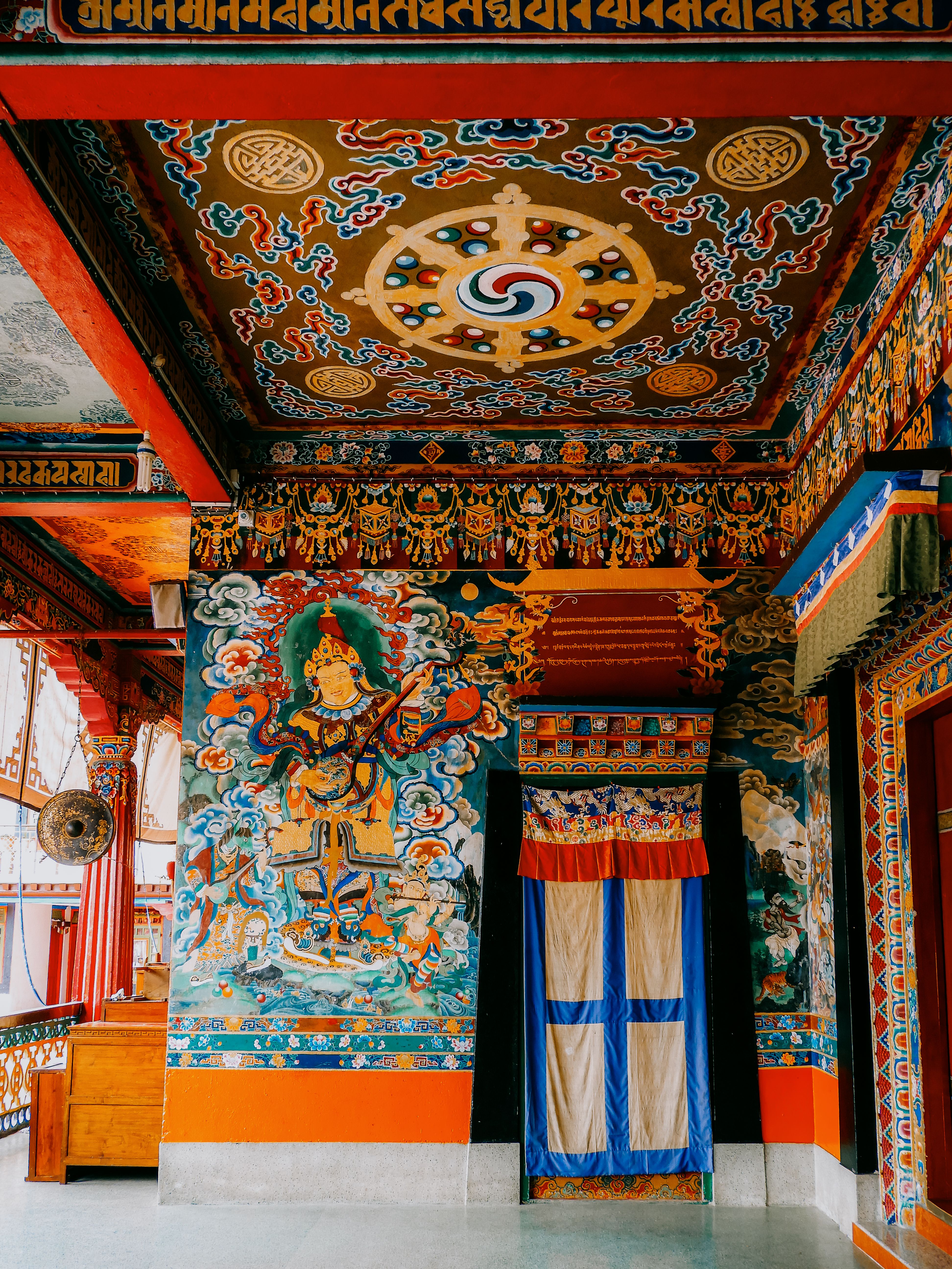 El pórtico pintado del monasterio de Rumtek, con un rey guardián que toca el laúd en la pared y un mandala en el techo