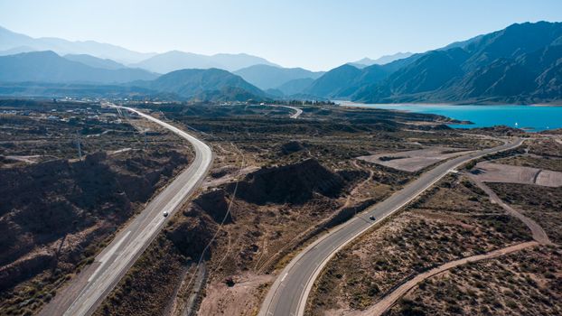 Dramatic aerial view of Potrerillos Lake and mountains in Mendoza, Argentina under clear skies.
