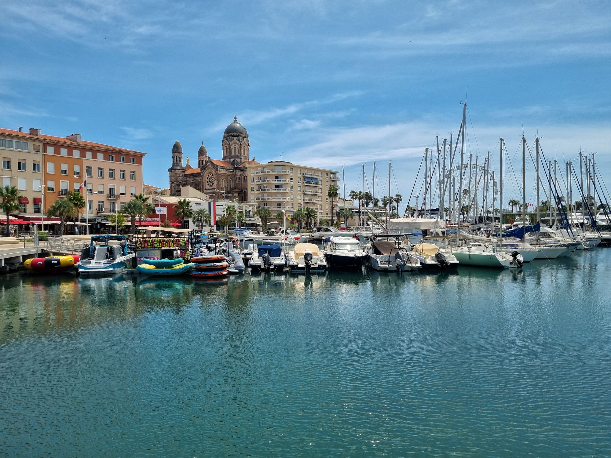 Scenic view of Saint-Tropez marina with boats and the iconic cathedral on a sunny day.