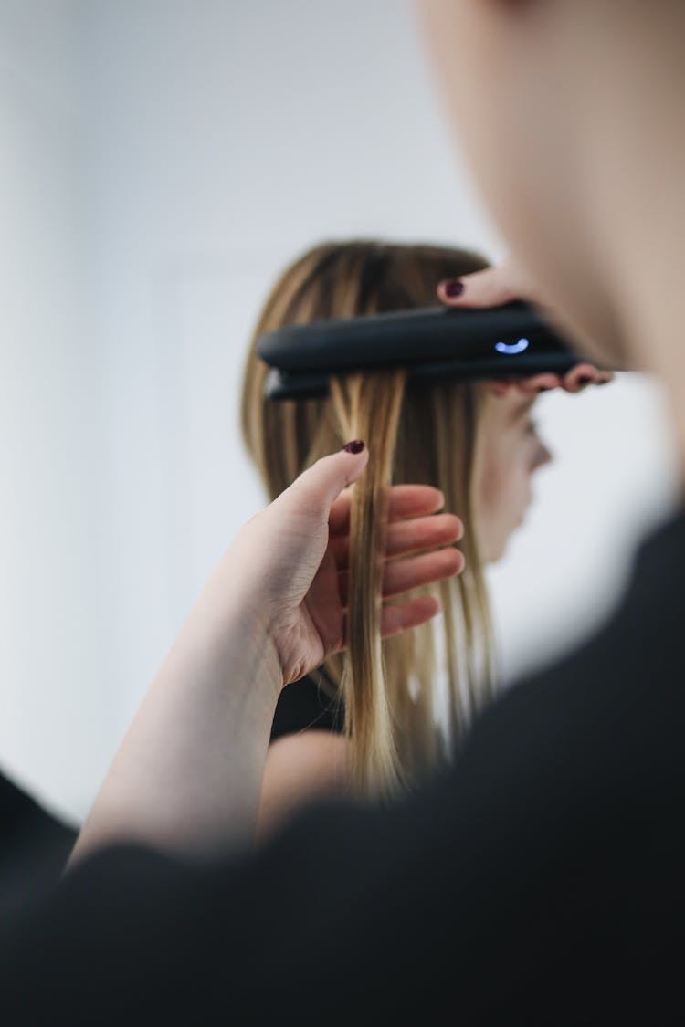 Selective Focus Photo Of Person Ironing A Woman's Hair