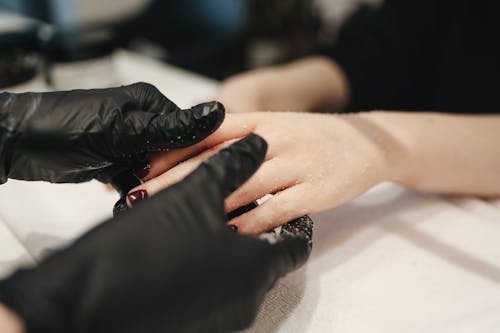 Person Wearing Black Gloves Massaging a Person's Hand
