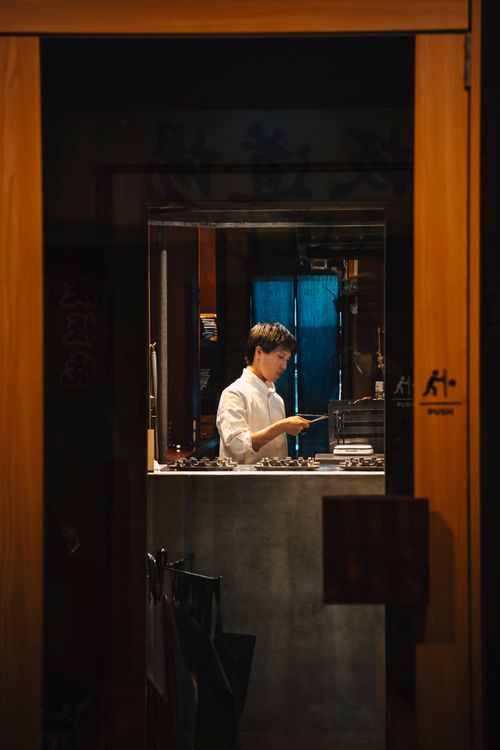 Free A focused chef prepares dishes inside a cozy Kyoto restaurant kitchen. Stock Photo