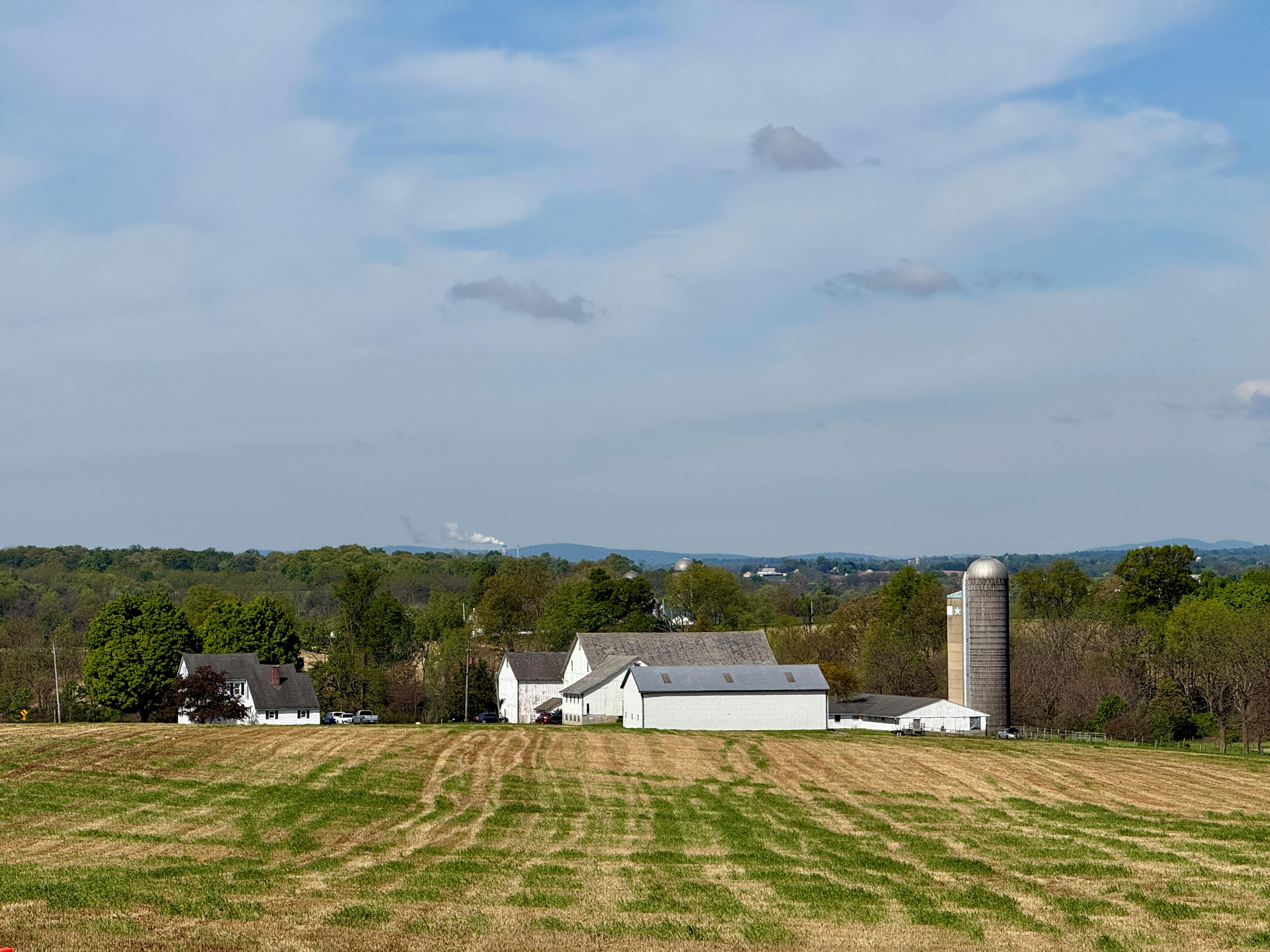 Sunny rural farm landscape in Pennsylvania with silo and white farmhouse