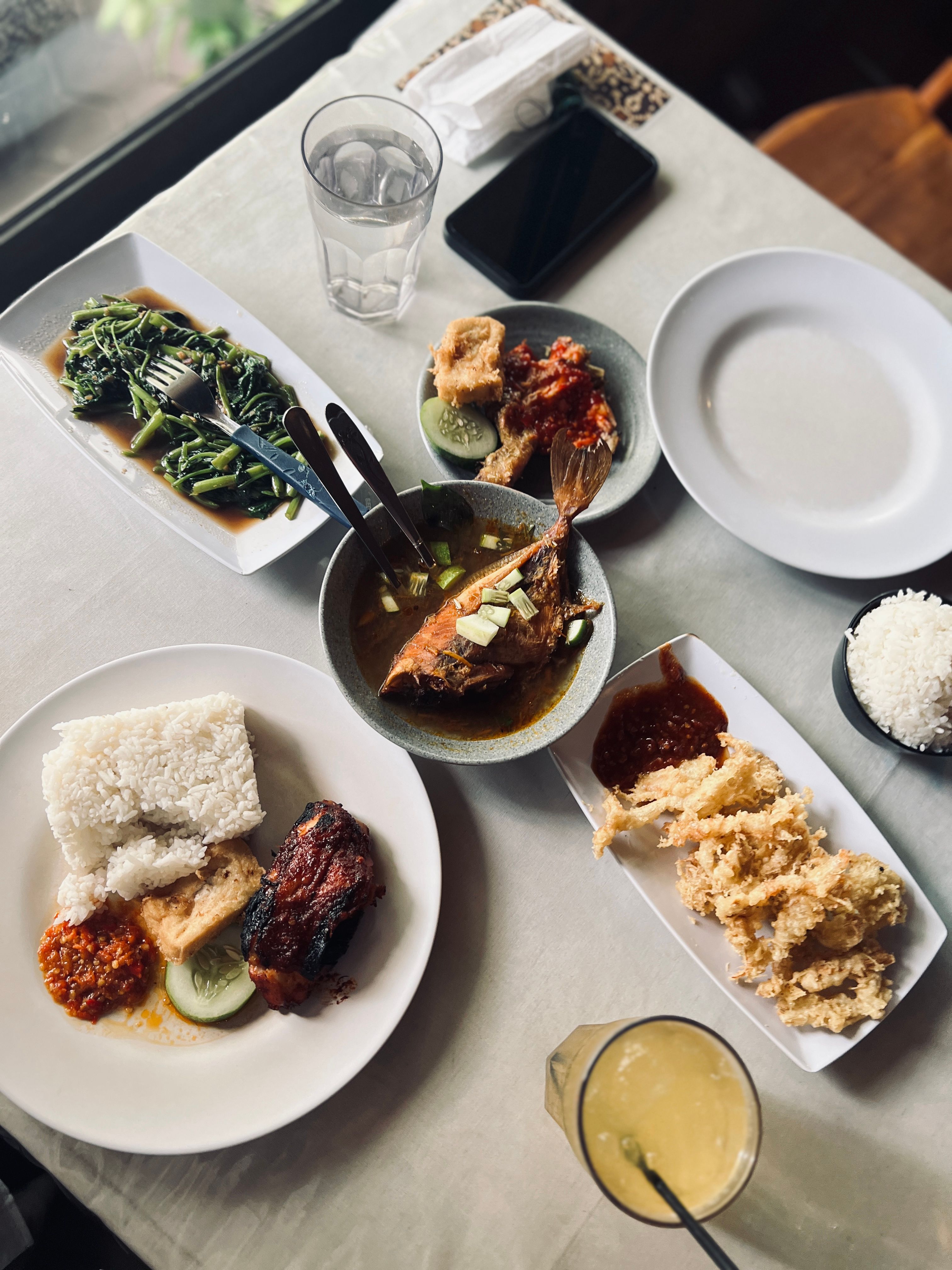 Delicious spread of Indonesian dishes including fried fish and vegetables.