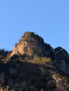 Stunning Seoraksan mountain peak bathed in sunlight against a clear blue sky, capturing nature's beauty.