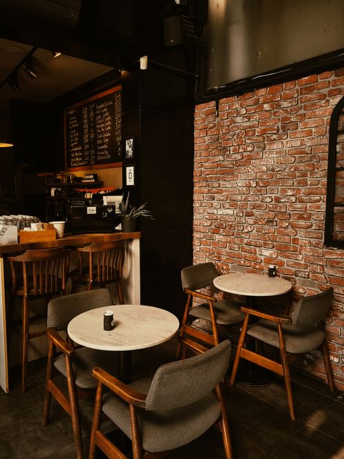 Free A warm and inviting café setting with a brick wall and wooden furniture, perfect for a tranquil coffee break. Stock Photo