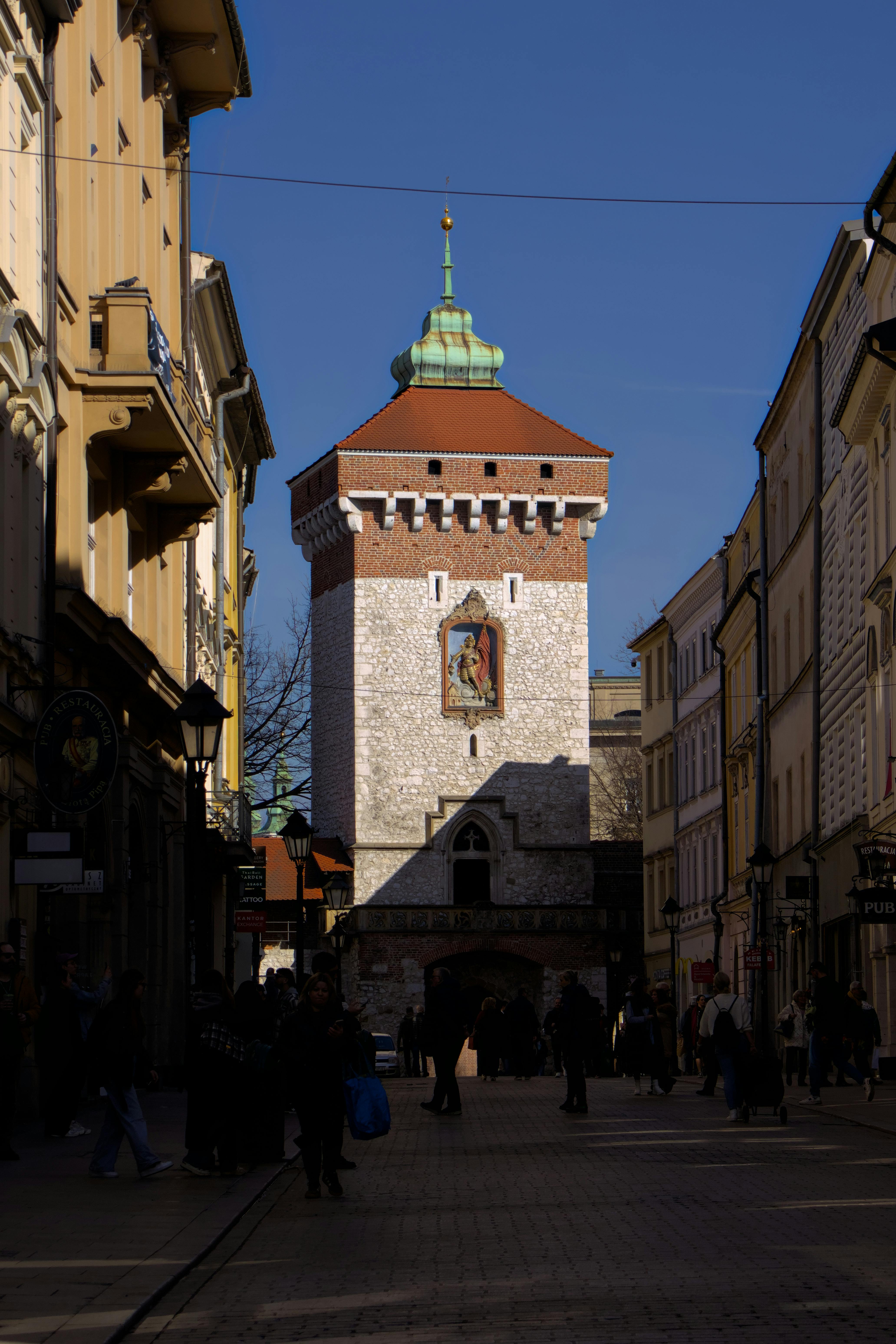 Street view of the historic Florian Gate in Kraków, showcasing medieval architecture.