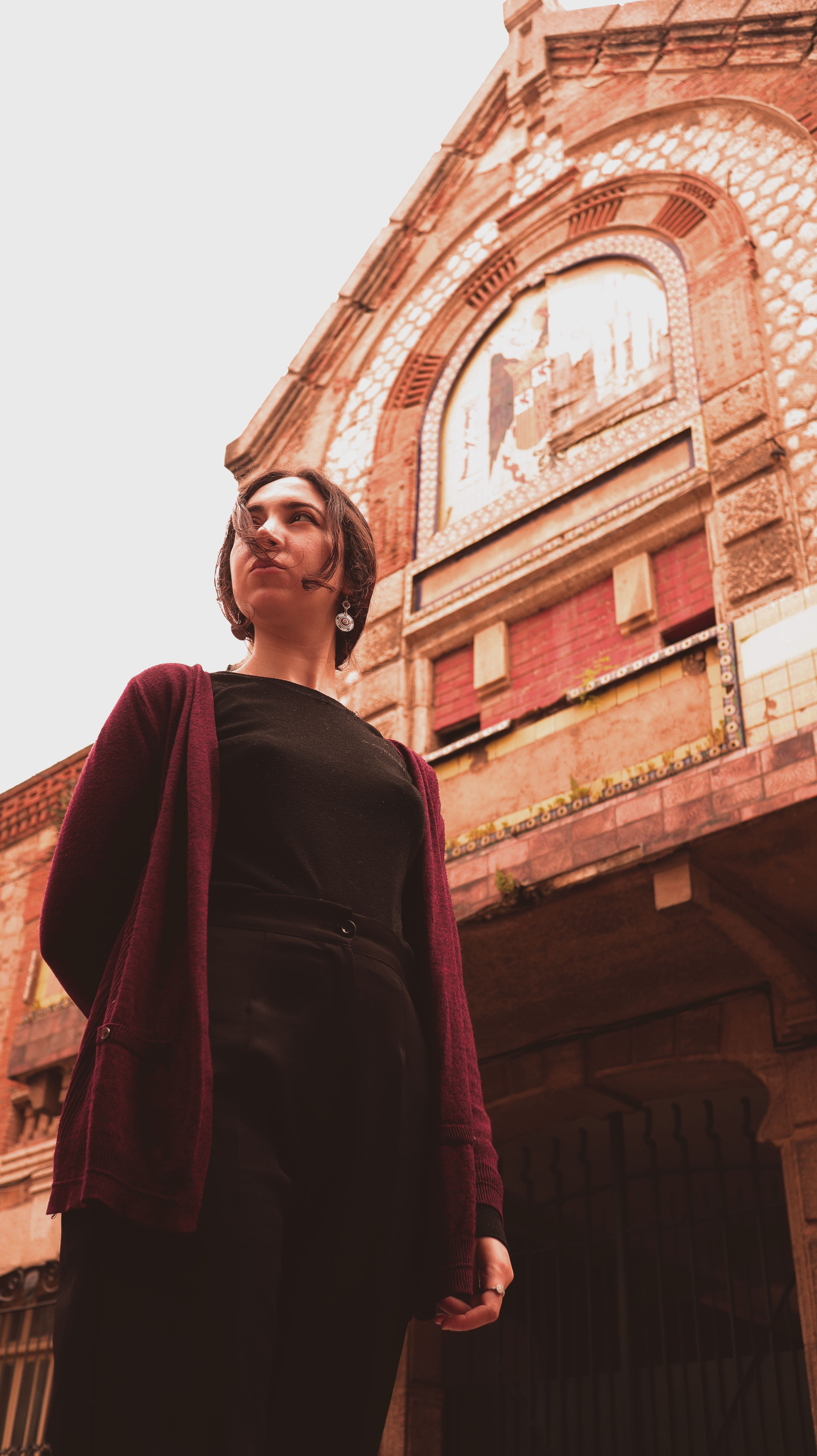 A woman stands confidently in front of a historic building, capturing a vintage urban scene.