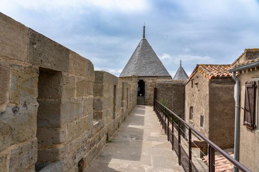 Stone pathway leading to conical-roofed towers in historic architecture.