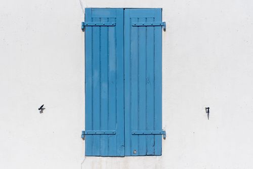 Free Clean and simple image of blue wooden shutters on a crisp white wall showcasing minimalistic design. Stock Photo
