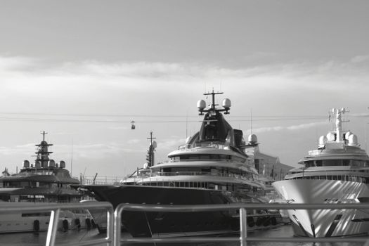 Black and white photo of luxury yachts docked at a harbor in Barcelona, Spain.
