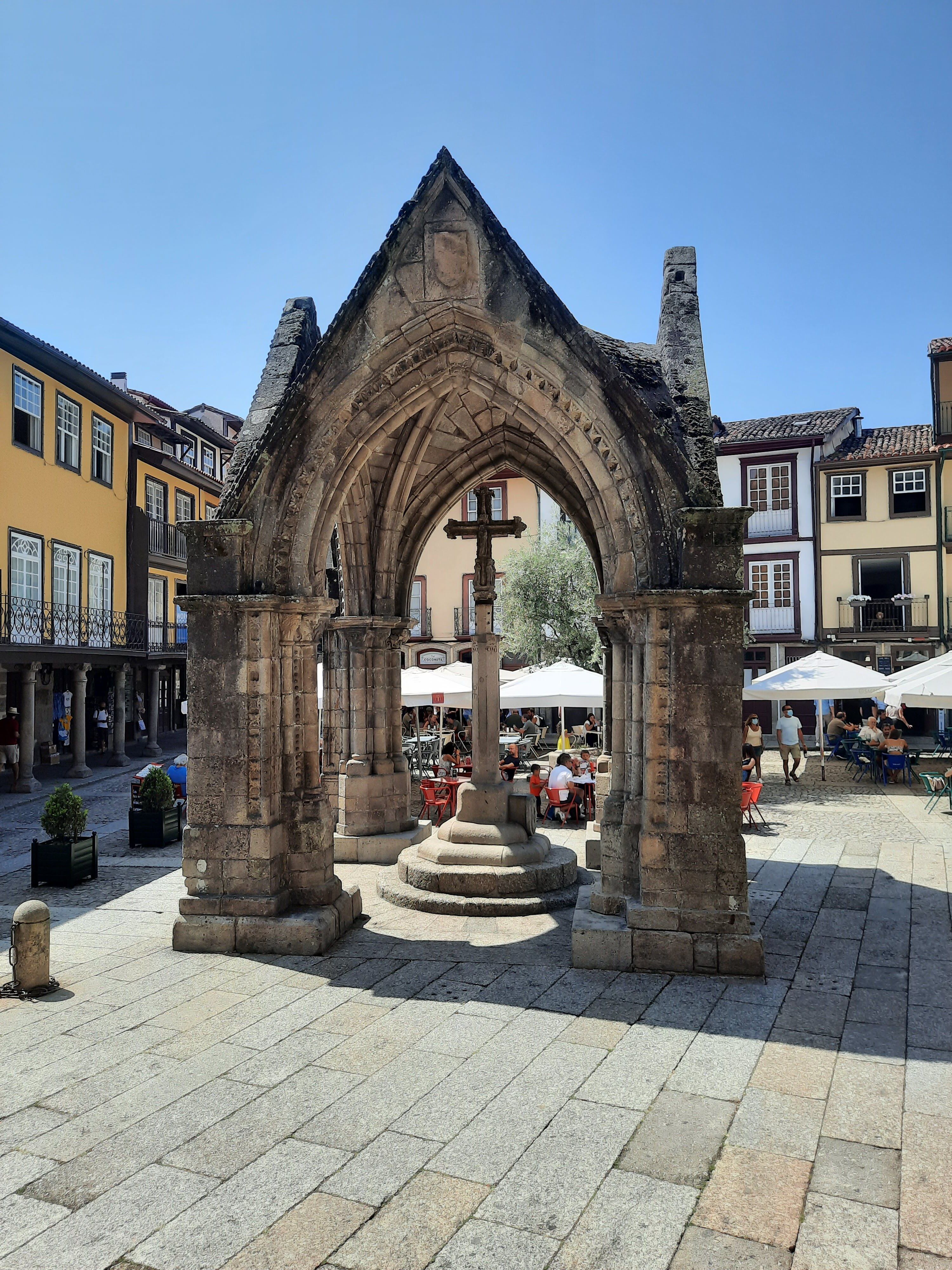 Scenic view of the Gothic monument in Largo da Oliveira, Guimarães, Portugal with people enjoying the day.