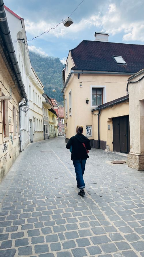 Free A person walking down a picturesque European alley lined with charming houses and cobblestones. Stock Photo