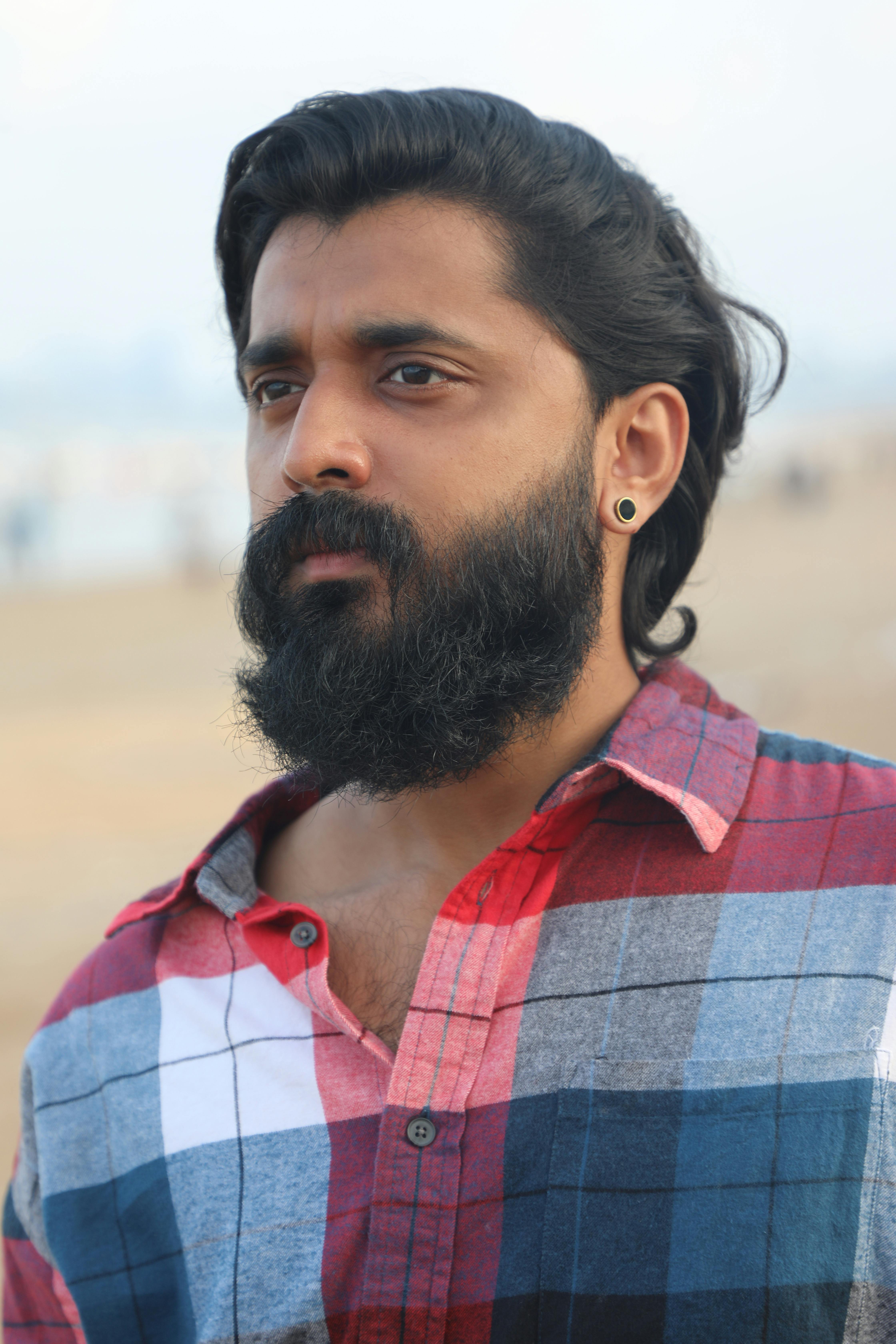 Portrait of a thoughtful bearded man wearing a plaid shirt by the seaside.