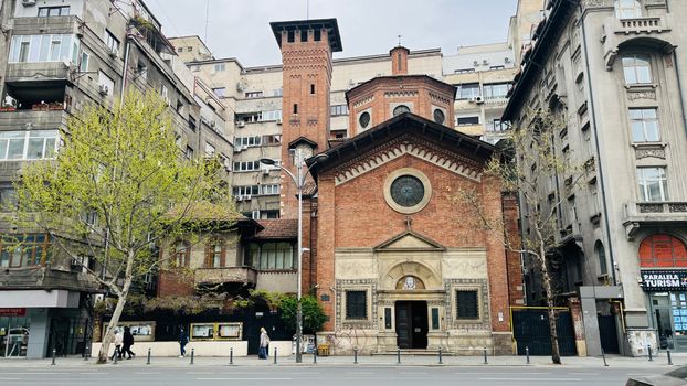 A historic brick church stands amidst modern urban buildings, showcasing architectural contrast.